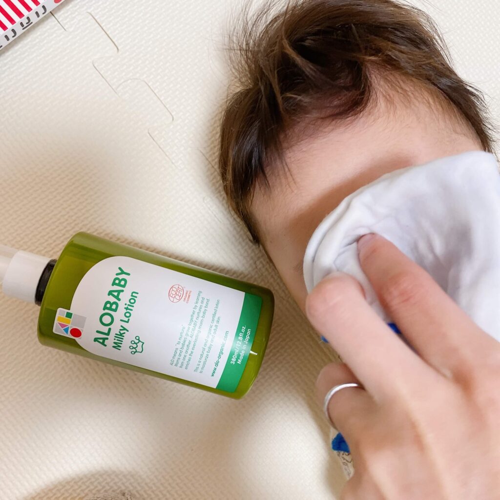 赤ちゃんの顔を手拭いで拭いて、ALOBABYの保湿剤で保湿